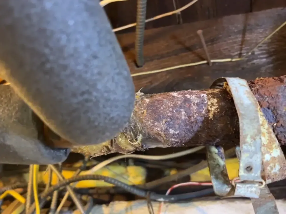 Corroded galvanized pipe with rust and a pipe clamp