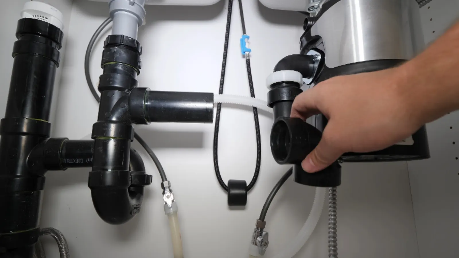 Hand fitting the drain connection onto a garbage disposal under a kitchen sink