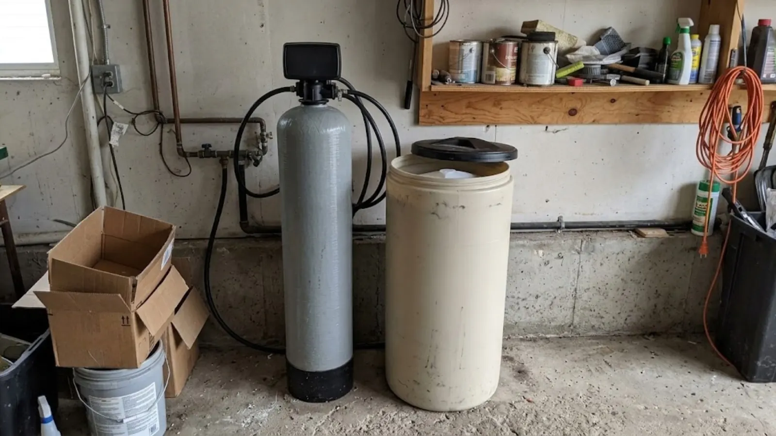 Water softener resin tank and brine tank standing against a garage wall